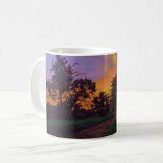 a painting on a coffee mug with trees in the background at sunset or sunrise time