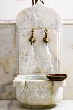 a white marble sink with two golden faucets on the front and back of it