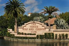 the venice golf and country club sign in front of palm trees, water and blue sky