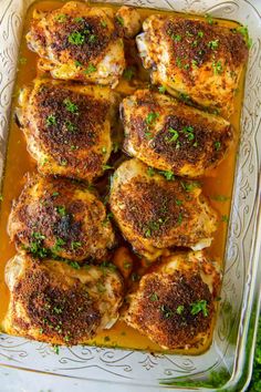 baked chicken thighs in a casserole dish with parsley on top and seasoning