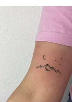 a woman's arm with a small mountain tattoo on the left side of her arm