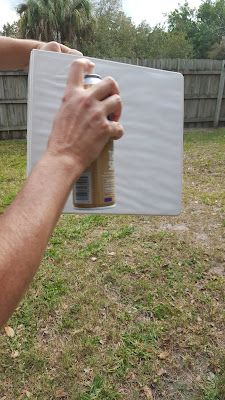 a person holding up a bottle of sunscreen in their hand, on the grass