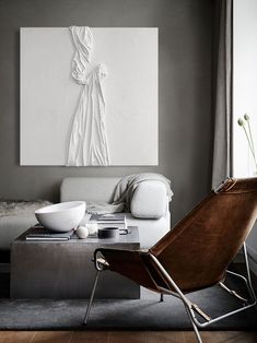 a living room with a couch, chair and artwork on the wall in front of it