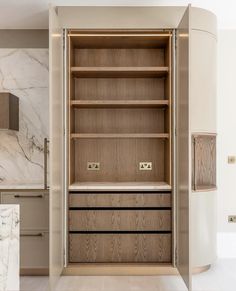 an open cabinet in the middle of a room with marble counter tops and cabinets on both sides