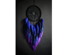 a purple and blue dream catcher hanging on a wall next to a black background with stars