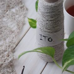 two spools of twine next to a cup of tea on a table