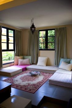 a living room filled with lots of furniture next to large windows and a rug on the floor