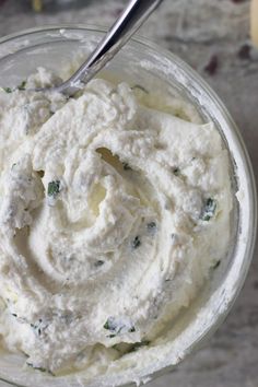 a glass bowl filled with mashed potatoes on top of a marble counter next to a metal spoon