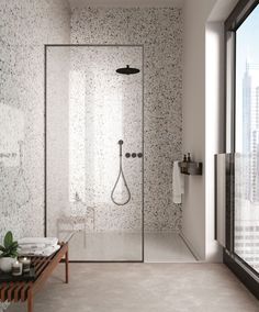 a bathroom with a walk in shower sitting next to a large window and a wooden bench