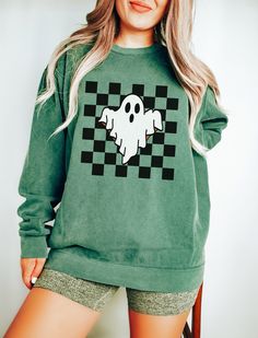 Checkered Ghost Sweatshirt. These sweatshirts are Comfort Colors. The comfort and style are what this unisex, garment-dyed sweatshirt is all about. It's made with 80% ring-spun cotton and 20% polyester and the fabric is 3-end garment-dyed, ring-spun, color-blast fleece with a 100% cotton face. Each sweatshirt comes with a relaxed fit, a rolled-forward shoulder, and a back neck patch.  ✦ 80% Ring-Spun Cotton, 20% Polyester ✦ Relaxed fit ✦ Medium-heavy fabric ✦ Sewn-in twill label ✦ Eco-friendly, Ethically Made & Sweatshop Free ✦ Printed to order with non-toxic ink ✦ Durable and Long-lasting ✦ Shirts are pre-shrunk but may shrink slightly after washing ✦ Made to order: *Please allow 2-5 business days to print before being shipped* Sizing Recommendation: ✦ See size guide in images above ✦ Thi Green Halloween Graphic Print Sweatshirt, Trendy Long Sleeve Halloween Sweatshirt, Ghost Crewneck, Halloween Crew Neck Sweatshirt With Screen Print, Retro Halloween T-shirt With Crew Neck, Washing And Drying Machine, Photo Care, The Only Exception, Comfort Colors Sweatshirt