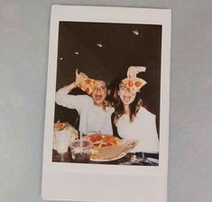 two people sitting at a table with pizza on their faces