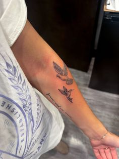 a woman's arm with two birds on it and one bird flying above the other