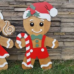 two wooden gingerbread man and woman standing next to each other in front of a brick wall