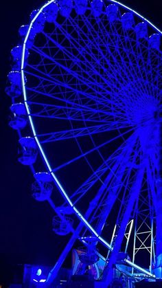 a ferris wheel lit up at night with blue lights on the top and bottom part