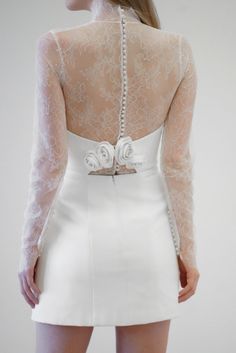 the back of a woman's white dress with long sleeves and flowers on it