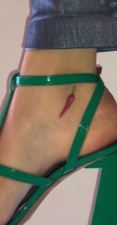 a woman's foot with a green ankle strap and red lipstick on the heel