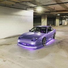 a purple car is parked in an empty parking garage with its hood up and lights on