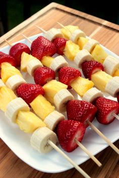 fruit skewers are arranged on a white plate