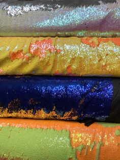 several different colored fabrics are stacked on top of each other, with one being sequinized