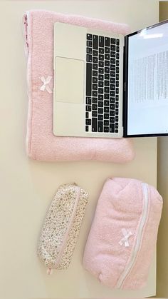 a laptop computer sitting on top of a desk next to a pink towel and mitt