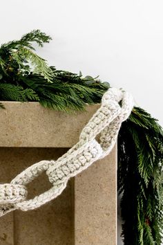 a crocheted white rope is tied to a fireplace mantel with evergreen branches