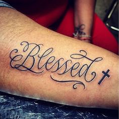 a person with a tattoo on their arm that reads, blessed and has a cross