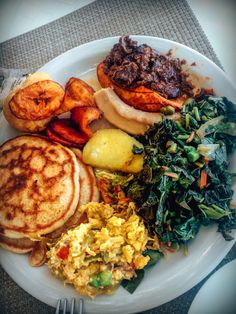 a white plate topped with breakfast foods on top of a table next to a fork