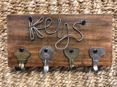 four keys hang on a wooden board with metal hooks and the word key's attached to it