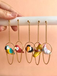 a person is holding four key chains with small birds on them, and one has a chain attached to it