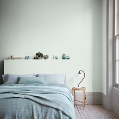 a bed sitting in a bedroom next to a window with green walls and wooden floors