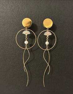 two pairs of gold toned earrings with white pearls hanging from the ends of each ear