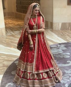 a woman in a red and gold bridal gown posing for the camera with her hand on her hip