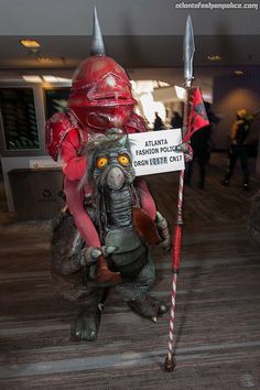 a man dressed as a creature holding a sign in his hand and wearing an antman costume