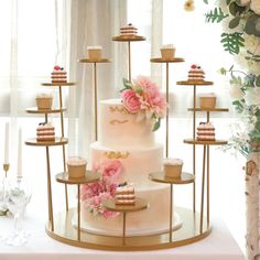 a three tiered cake with flowers on the top is surrounded by other desserts