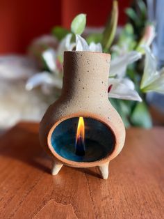 a small ceramic vase with a lit candle in it on top of a wooden table