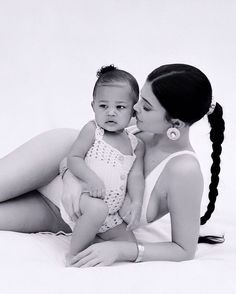 a woman holding a baby while laying on the ground