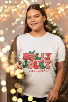 a woman wearing a holly jolly teacher t - shirt in front of a christmas tree