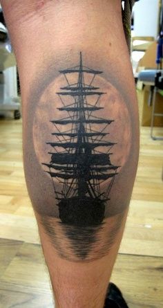 a man's leg with a black and white tattoo of a ship on it