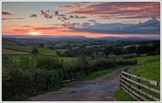 the sun is setting over an open field with hills and fields in the back ground