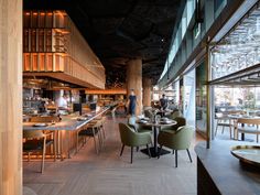 an empty restaurant with tables and chairs in front of large windows, people are eating at the counter