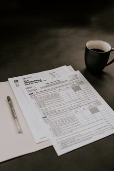 a cup of coffee sitting on top of a table next to a piece of paper