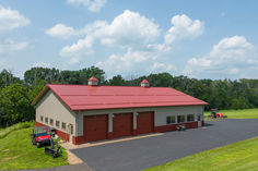 an overhead view of a red and white barn with two tractors parked in the driveway