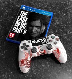 the last of us part ii is on display next to a video game controller with blood splatters all over it