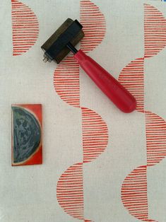 a red brush sitting on top of a piece of fabric next to a stamp and a rubber pad