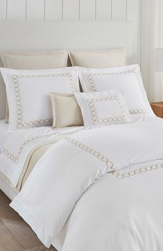 a bed with white sheets and pillows on top of it