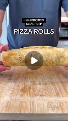 a person holding a piece of pizza on top of a wooden cutting board