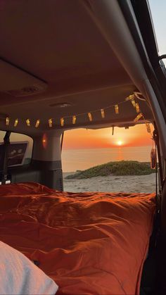 the sun is setting in the back of a van with an orange blanket on it