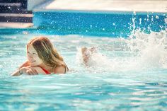 a woman swimming in a pool with splashing water