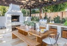 an outdoor kitchen and dining area with wood table, grilling oven and seating areas