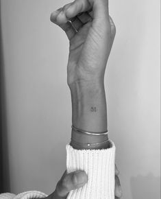 a woman's hand with a small tattoo on her wrist and the other arm